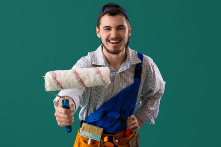 Male decorator with paint roller on green backgroundの写真素材