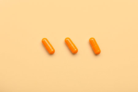 Orange medical capsules on beige backgroundの写真素材