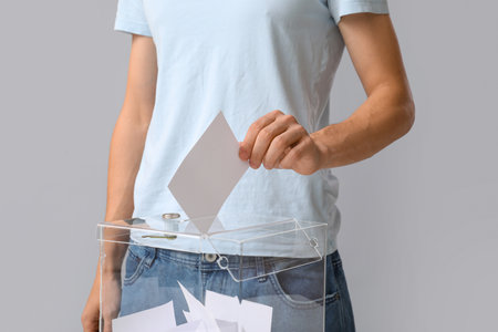 Voting young man near ballot box on light background, closeupの写真素材