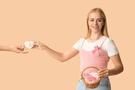 Young woman giving baked cookie on beige background. Breast cancer awareness conceptの写真素材