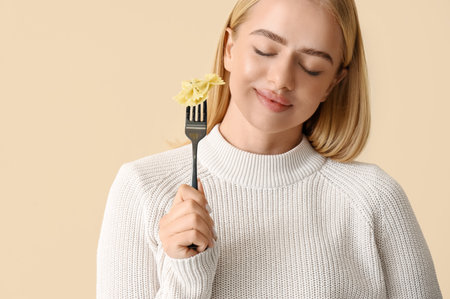 Young woman eating tasty pasta on beige background, closeupの写真素材