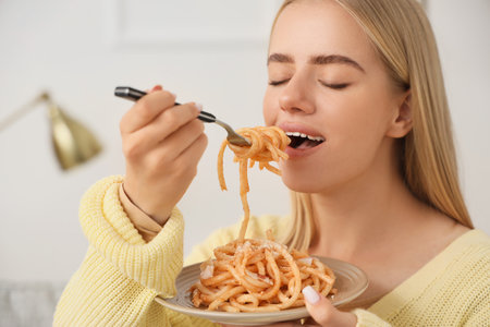 Young woman eating tasty pasta at home, closeupの写真素材