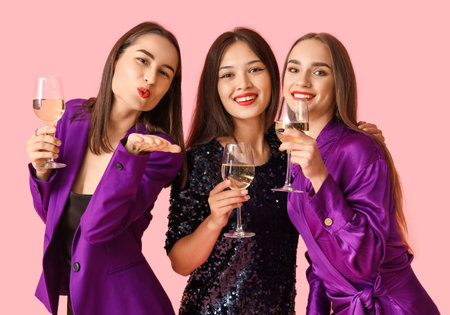 Young women with champagne on pink background. New Year celebrationの写真素材