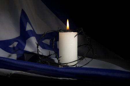Burning candle with barbed wire on flag of Israel, closeup. International Remembrance Dayの写真素材