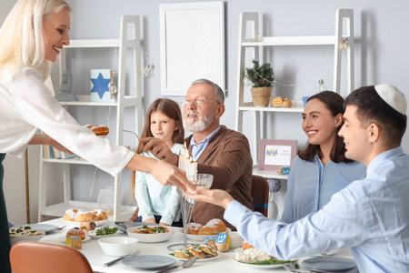 Happy little girl having dinner with her family at home on Hanukkahの写真素材