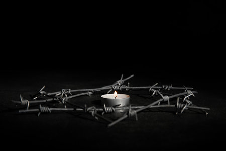 Burning candle with barbed wire on dark background. International Holocaust Remembrance Dayの写真素材