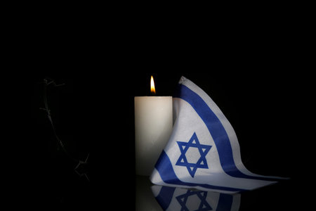 Burning candle with flag of Israel and barbed wire on dark background. International Holocaust Remembrance Dayの写真素材