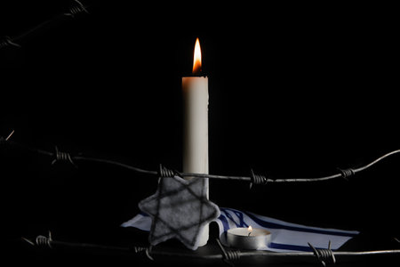 Burning candles with Jewish badge, flag of Israel and barbed wire on dark background. International Holocaust Remembrance Dayの写真素材
