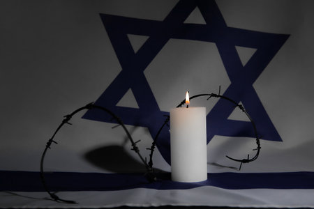 Burning candle with barbed wire on flag of Israel. International Holocaust Remembrance Dayの写真素材