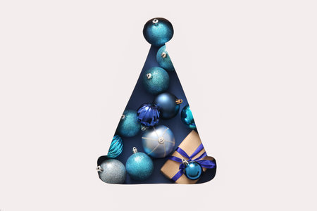 Cut white paper in the shape of Santa hat with gift and balls on blue backgroundの写真素材