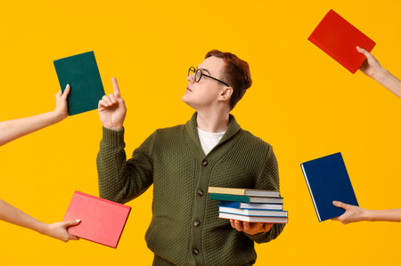 Young man and female hands with different books on yellow backgroundの写真素材