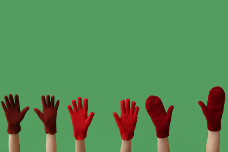 Female hands in warm gloves and mittens on green backgroundの写真素材