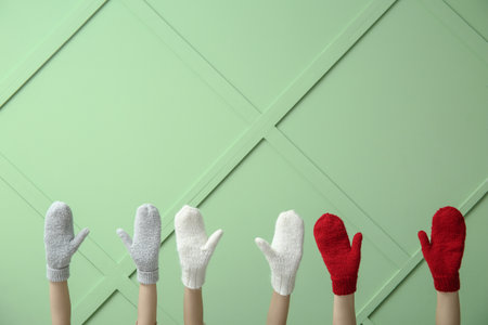 Female hands in warm mittens against color wallの写真素材