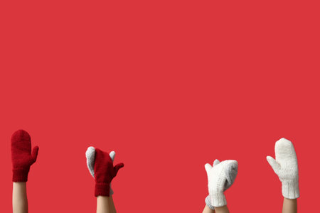 Female hands in stylish warm mittens on red backgroundの写真素材