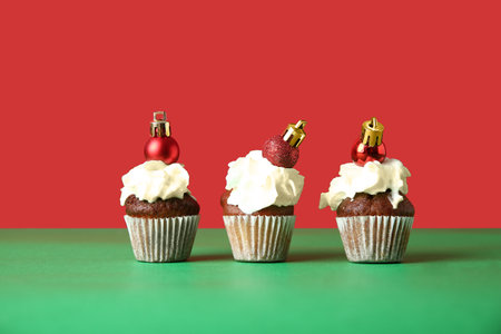 Sweet cupcakes with Christmas balls on color backgroundの写真素材