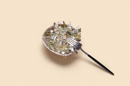 Bowl with beautiful Christmas tinsel and fork on color backgroundの写真素材