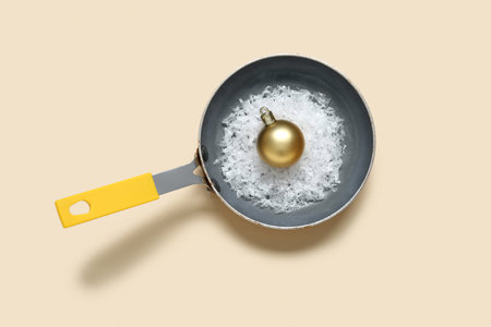 Frying pan with artificial snow and Christmas ball on color backgroundの写真素材