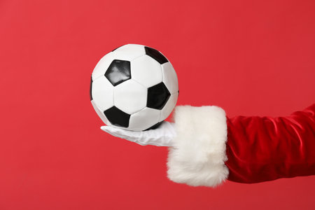 Santa hand with soccer ball on red background, closeupの写真素材