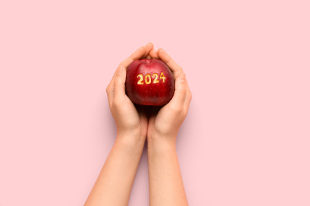 Apple with carved figure 2024 in female hands on color background, closeupの写真素材
