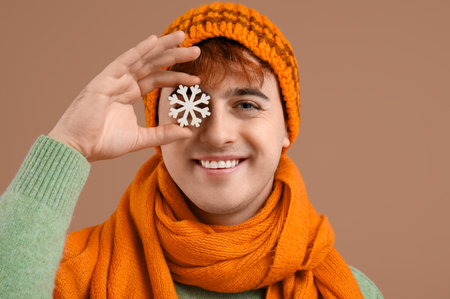 Young man in winter clothes with snowflake on brown background, closeupの写真素材