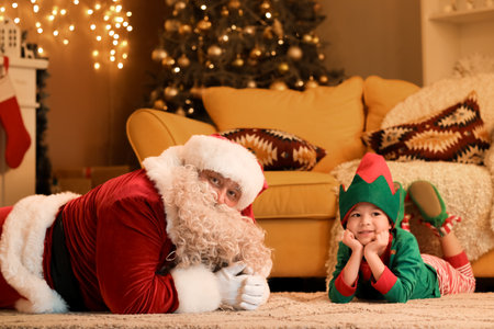 Santa Claus with cute little elf at home on Christmas Eveの写真素材