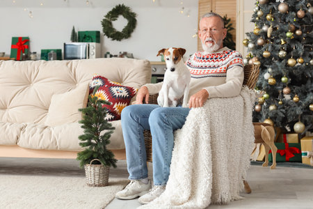 Mature man with cute dog in armchair at home on Christmas Eveの写真素材