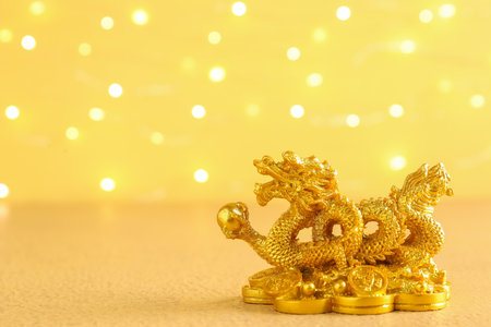 Golden dragon figurine on yellow background, closeup. Chinese New Year celebrationの写真素材