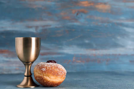 Tasty sufganiyot and goblet on blue wooden background. Hanukkah celebrationの写真素材