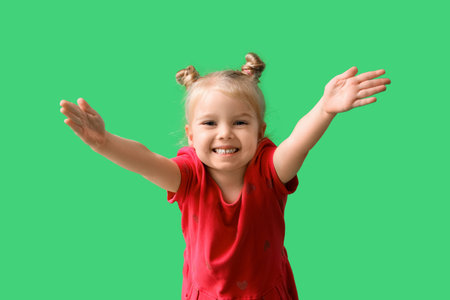 Cute little girl opening arms for hug on green backgroundの写真素材