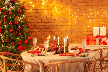 Dining table with Christmas setting and burning candles in roomの写真素材