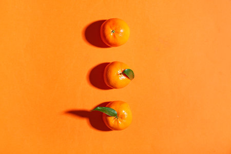Sweet mandarins with leaves on orange backgroundの写真素材