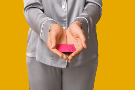 Beautiful young woman with condom on yellow background, closeup. Safe sex conceptの写真素材