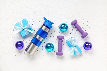 Composition with bottle of water, dumbbells and Christmas gifts and balls on light backgroundの写真素材