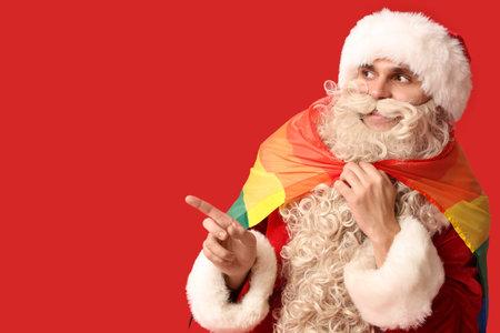 Santa Claus with LGBT flag pointing at something on red backgroundの写真素材