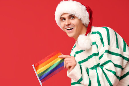 Young man in Santa hat with LGBT flag on red backgroundの写真素材