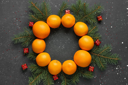 Frame made of tasty oranges with fir branches and Christmas gift boxes on black backgroundの写真素材