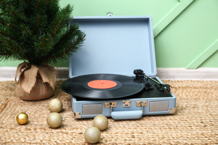 Vintage record player, Christmas tree and balls on floor near color wallの写真素材