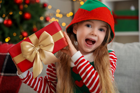 Happy little elf with Christmas gift at home