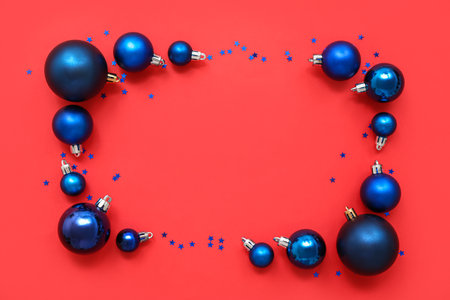 Composition with frame made of blue Christmas balls with sparkles on red backgroundの写真素材