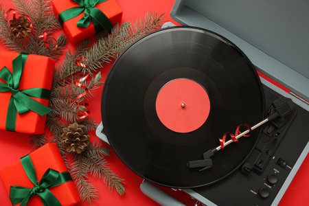 Vinyl record player and Christmas gifts on red backgroundの写真素材