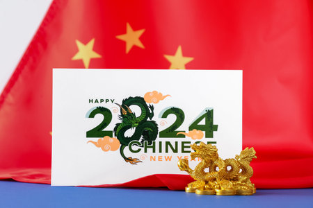 Golden dragon figurine with greeting card and flag of China on blue table. Chinese New Year celebrationの写真素材