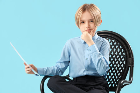 Little actor with film script sitting in chair on blue backgroundの写真素材