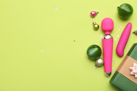 Gift box with vibrators and Christmas decor on green backgroundの写真素材