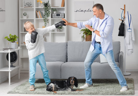 Mature doctor with his little son boxing at home