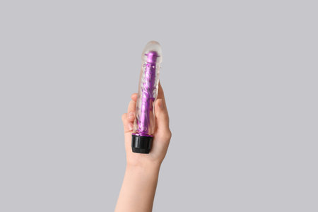 Female hand with vibrator on gray background, closeup