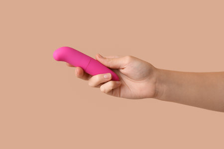 Female hand with pink vibrator on color background, closeupの写真素材