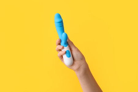Female hand with vibrator on yellow background, closeupの写真素材