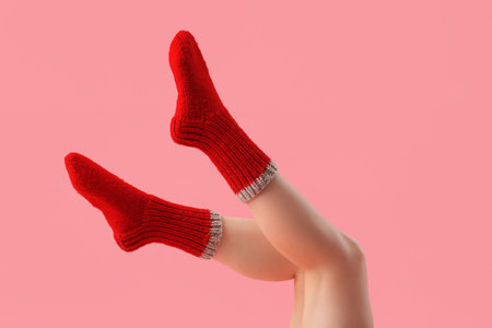 Legs of young woman in red knitted socks on pink backgroundの写真素材