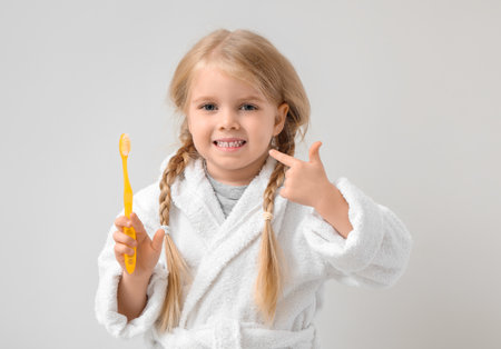 Cute little girl pointing at toothbrush on white backgroundの写真素材