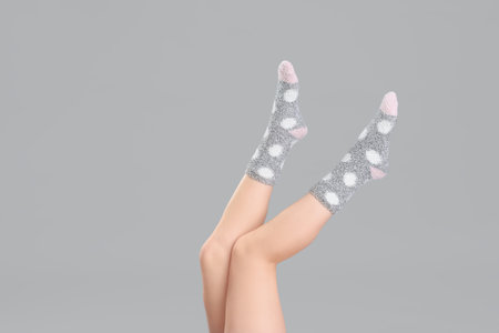Legs of young woman in warm socks on gray backgroundの写真素材